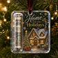 A clear acrylic Christmas ornament hanging on a decorated Christmas tree. The ornament contains a rolled dollar bill in a clear tube and features a printed holiday scene with the text 'Home for the Holidays' and a snowy house with warm lights.