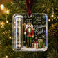 A Christmas ornament hanging on a tree branch, featuring a nutcracker figure, a rolled dollar bill inside a clear tube, and the text 'Crack Open Some Christmas Cash' with gift boxes and snowflakes on a dark background.