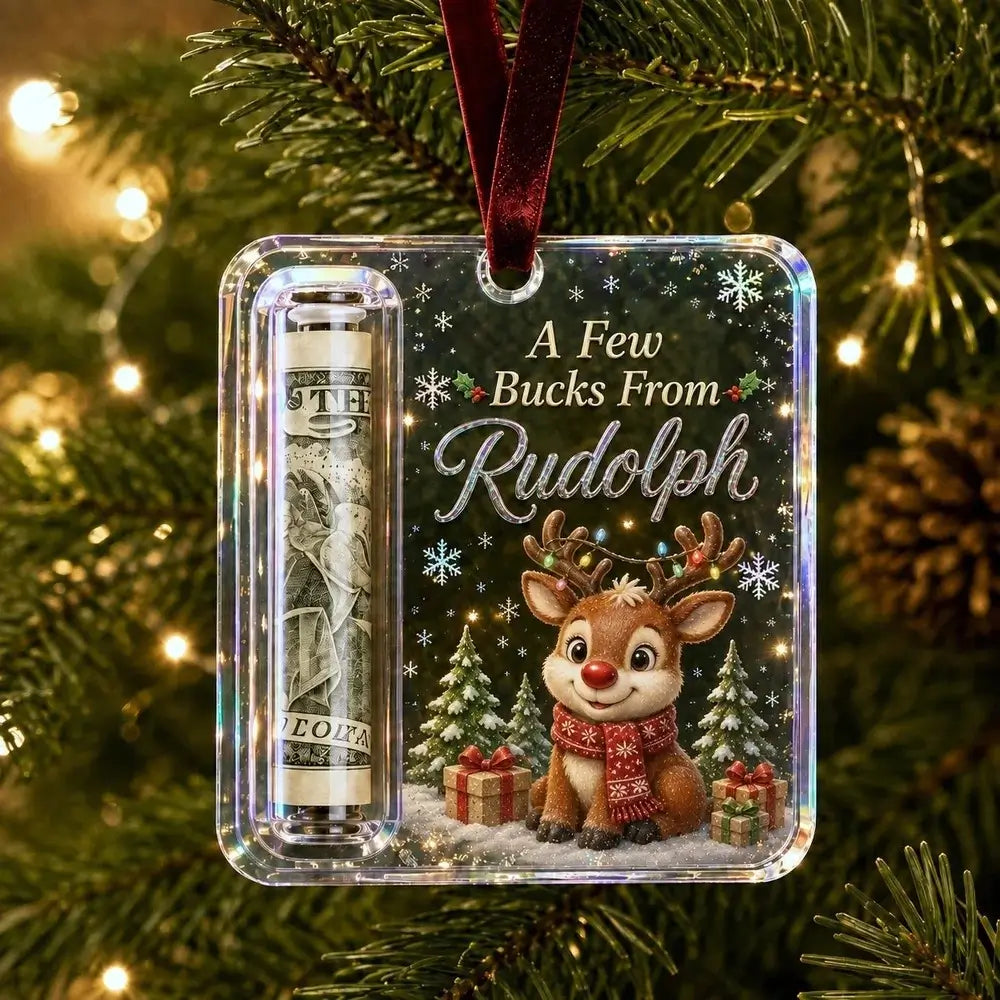 A personalized Christmas ornament hanging on a decorated Christmas tree. The clear square ornament features a printed design with the text 'A Few Bucks From Rudolph' above an illustration of a reindeer wearing a red scarf, a dollar bill roll, snowflakes, and holiday trees.