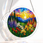 A round acrylic suncatcher showing a stained glass sunlit wildflower valley with iris tulips pine trees and distant mountains