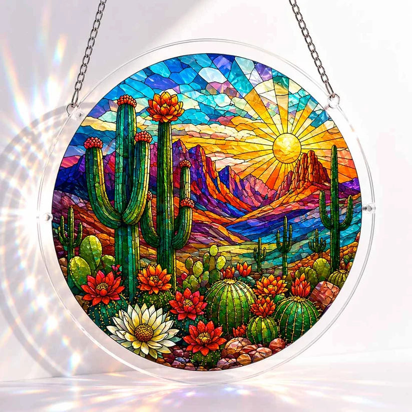 A round acrylic suncatcher depicting a desert sunset with saguaro cacti blooming cactus flowers and rocky mountains