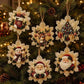 Six decorative Christmas ornaments shaped like snowflakes hang on a lit Christmas tree. The ornaments feature festive designs including a stocking, reindeer, Christmas tree, snowman, Santa Claus, and Santa face, all in warm cream, red, green, and gold tones.