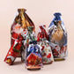 Six Christmas-themed clear plastic drawstring gift bags with white ribbons, decorated with festive illustrations including Santa Claus, reindeer, a Christmas house, and holiday motifs, arranged on a light beige background.