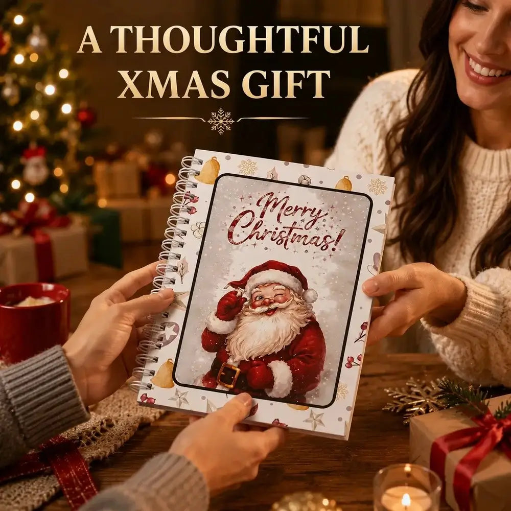 A spiral-bound notebook with a festive Christmas cover featuring Santa Claus and the text 'Merry Christmas!' is held by two people in a warmly lit holiday setting. Large text at the top reads 'A THOUGHTFUL XMAS GIFT'.