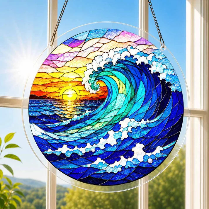 A round acrylic suncatcher with a great wave ocean scene and sunset hanging from a chain in front of a bright white window