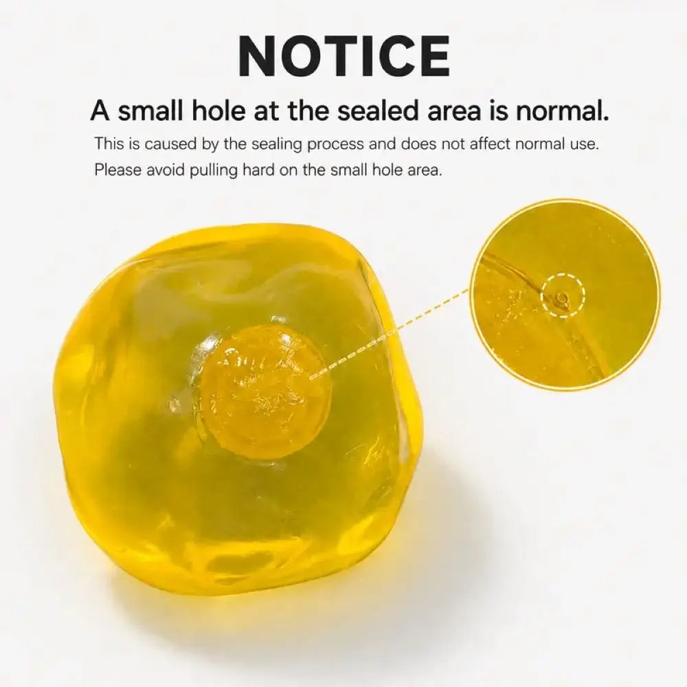 A translucent yellow coconut oil ball on a white background with printed text explaining that a small hole at the sealed area is normal and showing a close-up inset of that hole.