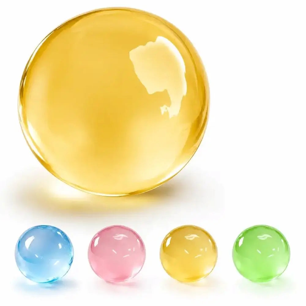 A large translucent yellow glass marble ball is shown above four smaller translucent glass marbles in blue, pink, yellow, and green, all on a white background.