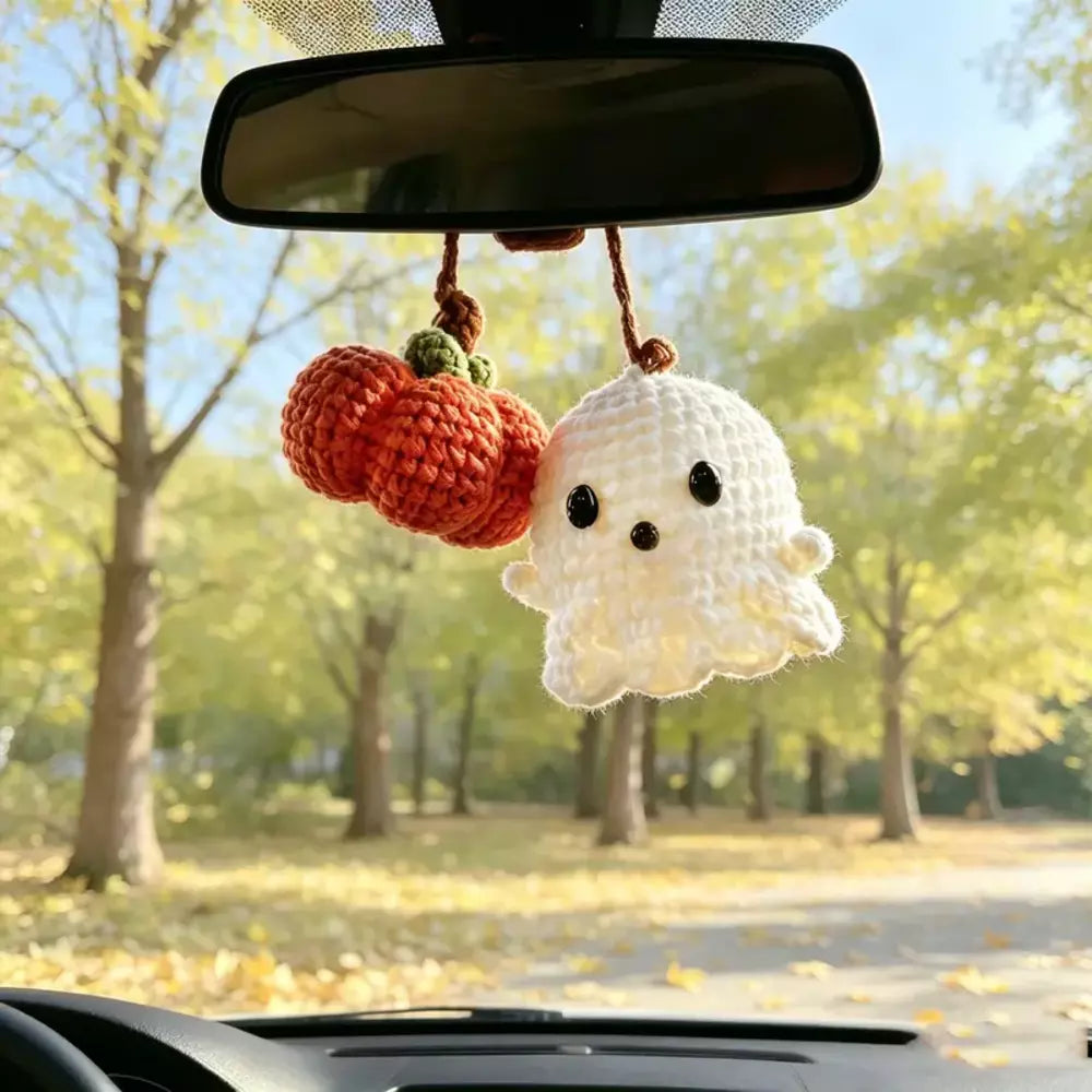 Crochet ghost and pumpkin charm hanging from a car rearview mirror