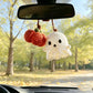 Crochet ghost and pumpkin charm hanging from a car rearview mirror