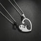 Two silver heart-shaped pendant necklaces on matching chains, designed to fit together into one heart. One pendant is polished silver with a black cat silhouette, and the other is black with a silver cat silhouette, set against a dark textured background.