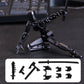 Black articulated sci-fi mecha action figure posed kneeling on a dark textured surface, with interchangeable weapon pieces and extra hands shown in a white panel at the bottom. A blurred keyboard is visible in the background.