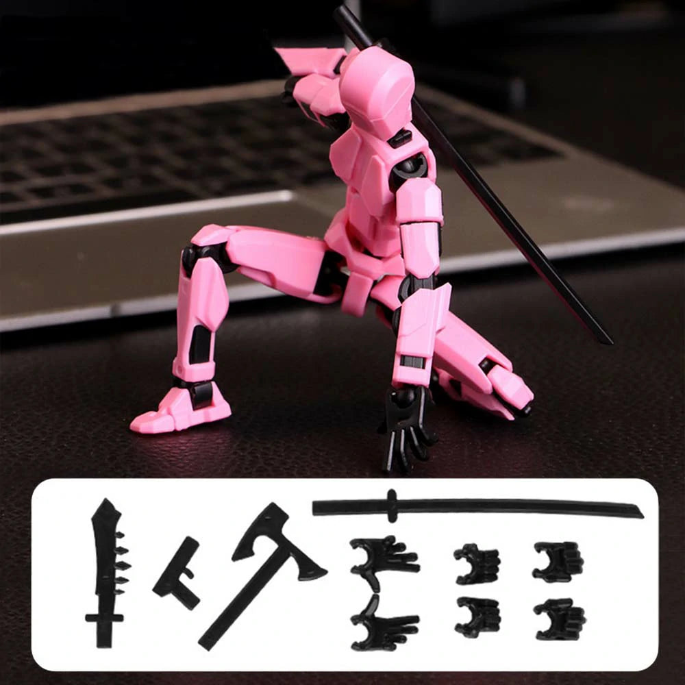 A pink articulated mecha action figure posed with a black sword on a dark tabletop, with a laptop blurred in the background and a white accessory panel showing additional black weapon and hand pieces.