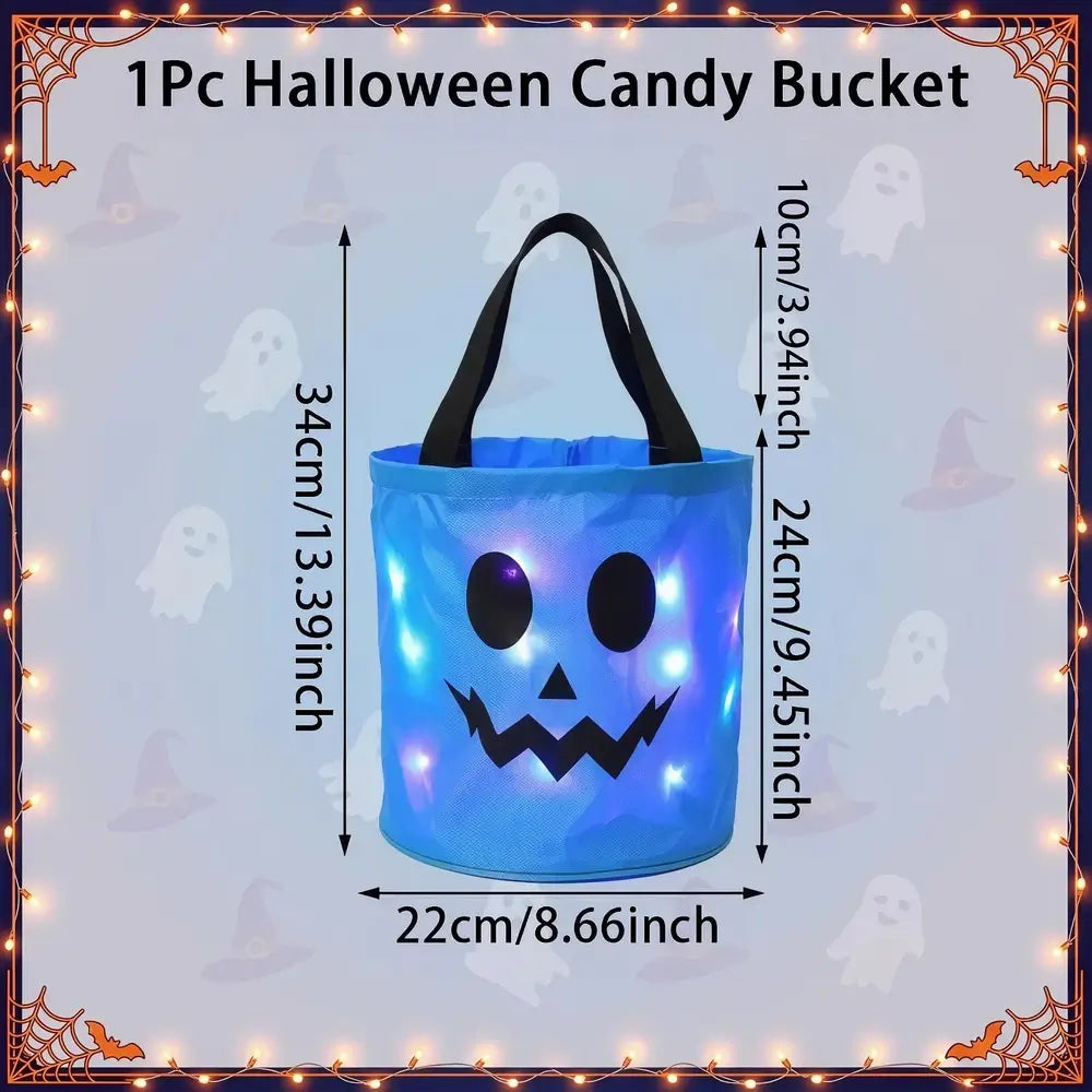 A blue inflatable Halloween candy bucket with black handles and a black jack-o'-lantern face, shown with printed dimension arrows and labels reading 34cm height, 24cm width, and 10cm handle width. The image has a decorative Halloween border with ghosts, bats, and string lights, and the text '1Pc Halloween Candy Bucket' at the top.