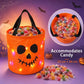 An orange pumpkin-shaped fabric candy bucket with black handles and a jack-o'-lantern face, filled with colorful wrapped candy. The image includes a circular inset showing the bucket from the back, text reading 'Accommodates Candy 22 cm x 24 cm,' a small pile of candy in front, and Halloween-themed background elements like bats, a moon, and cobwebs.