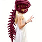 A woman wearing a large plush dinosaur skull headpiece with a long dark red tail spine, posed against a plain white background.