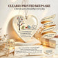 Heart-shaped ceramic keepsake plaque with a bird and tree illustration and a printed friendship message, displayed with a gift box, string lights, and decorative text on a warm beige background.