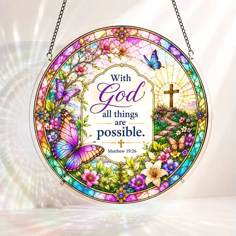A round acrylic suncatcher decorated with butterflies flowers and a cross featuring the bible verse with God all things are possible