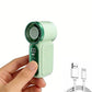 A handheld mini fan in mint green and dark green, held by a person's hand against a white background, with a white USB charging cable shown in the lower right corner.