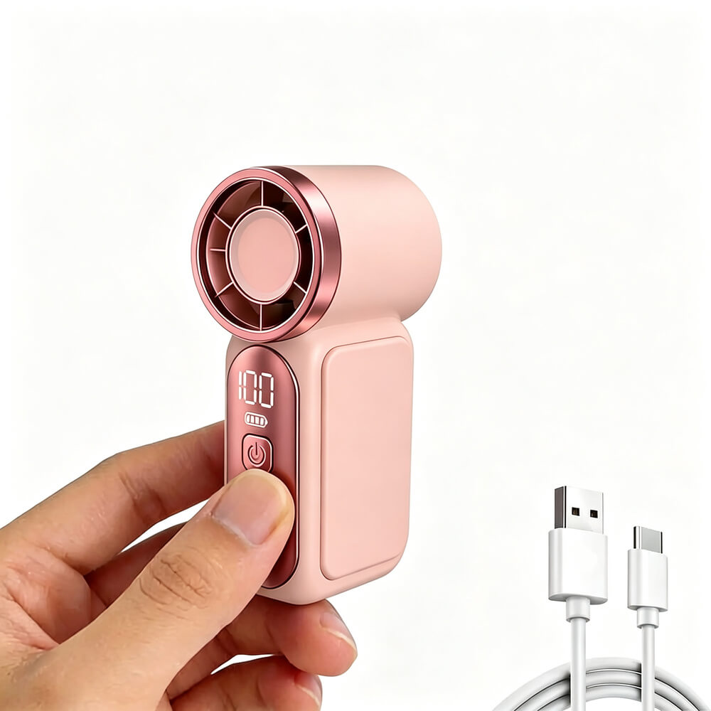 A hand holds a small pink handheld fan with a metallic rose-gold circular face and a digital display showing 100%. A white USB charging cable appears at the lower right on a clean white background.