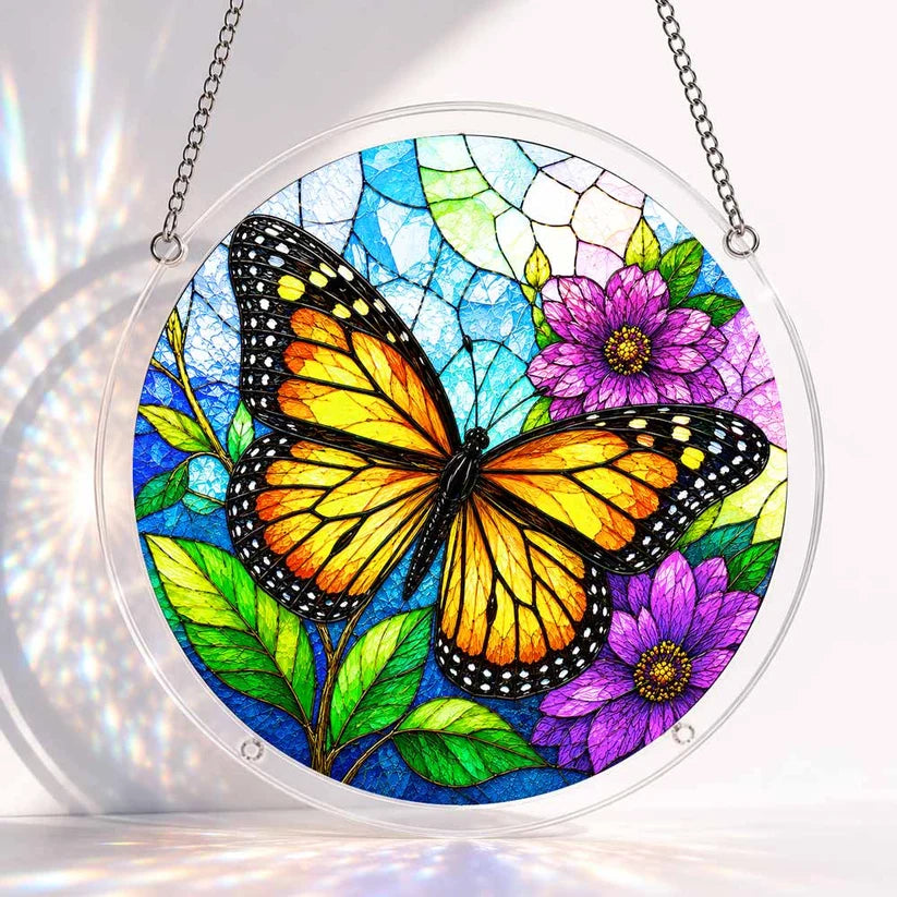 A round acrylic suncatcher with an orange black monarch butterfly beside purple flowers and green leaves