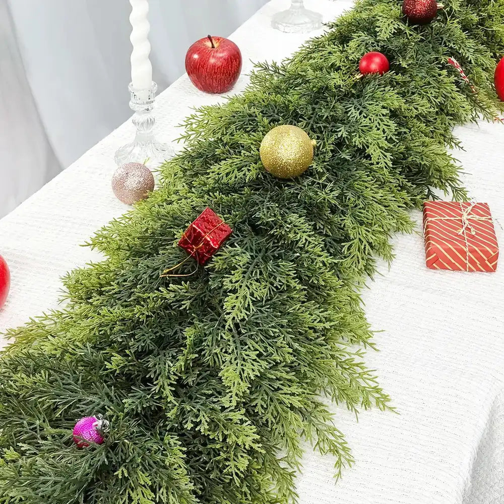 Decorative green garland with red and gold ornaments on a white surface