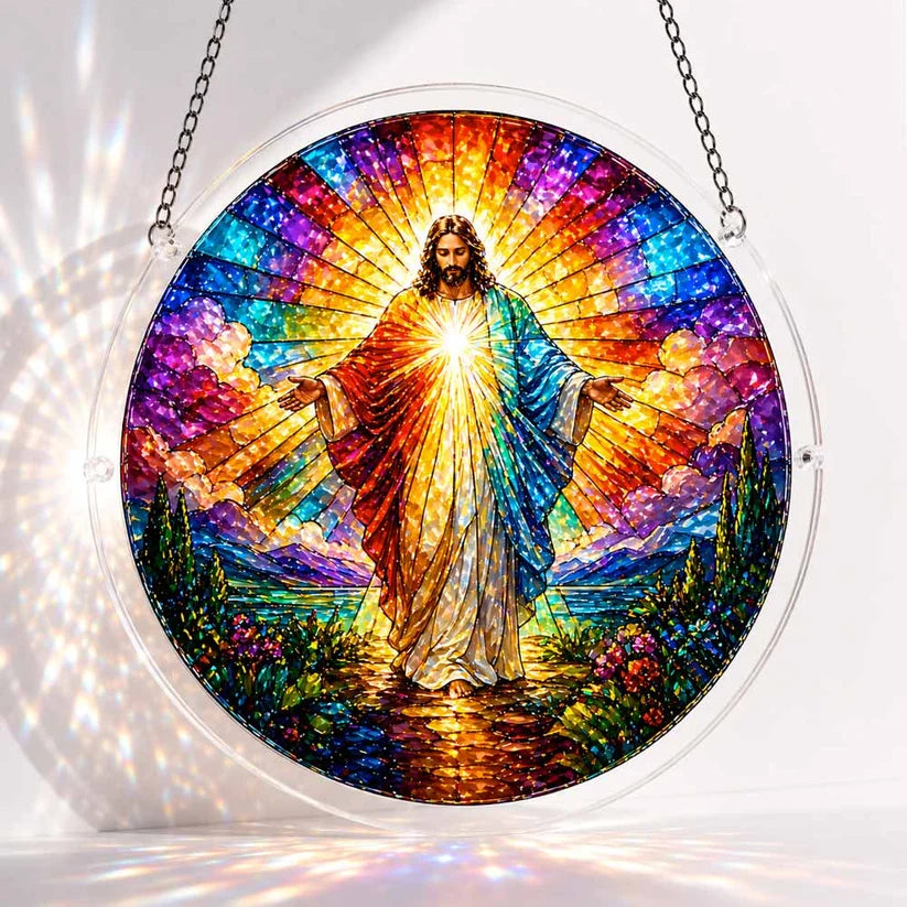 A round acrylic suncatcher depicting a radiant Jesus figure with open arms surrounded by rainbow light clouds and mountains