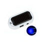 A white and black solar-powered USB charger with a circular inset showing a blue LED light, set against a plain white background.