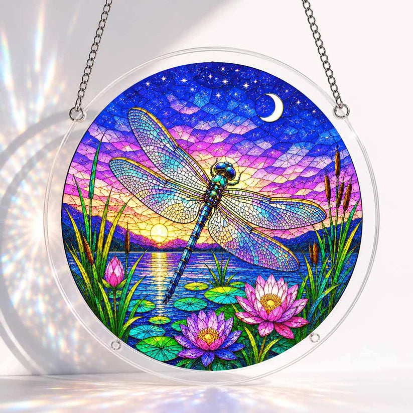 A round acrylic suncatcher with a blue dragonfly hovering over pink lotus flowers and a calm lake at twilight