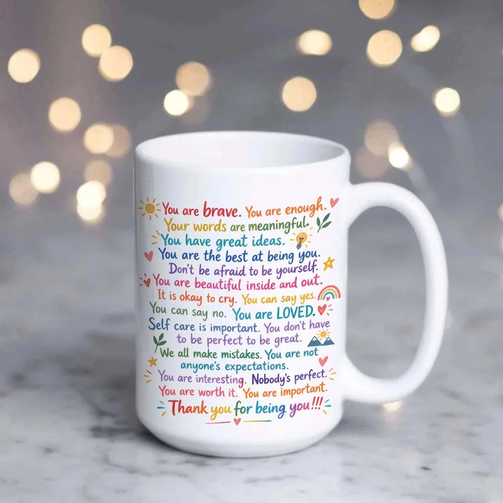 A white ceramic mug with colorful printed positive affirmation text.