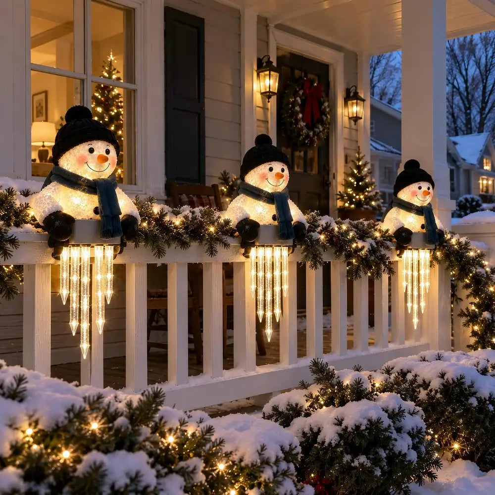 Three snowman holiday light decorations with warm white string lights are displayed on a snowy front porch with garlands and Christmas trees.