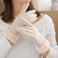 A close-up of a person wearing off-white winter gloves, paired with a white ribbed sweater.